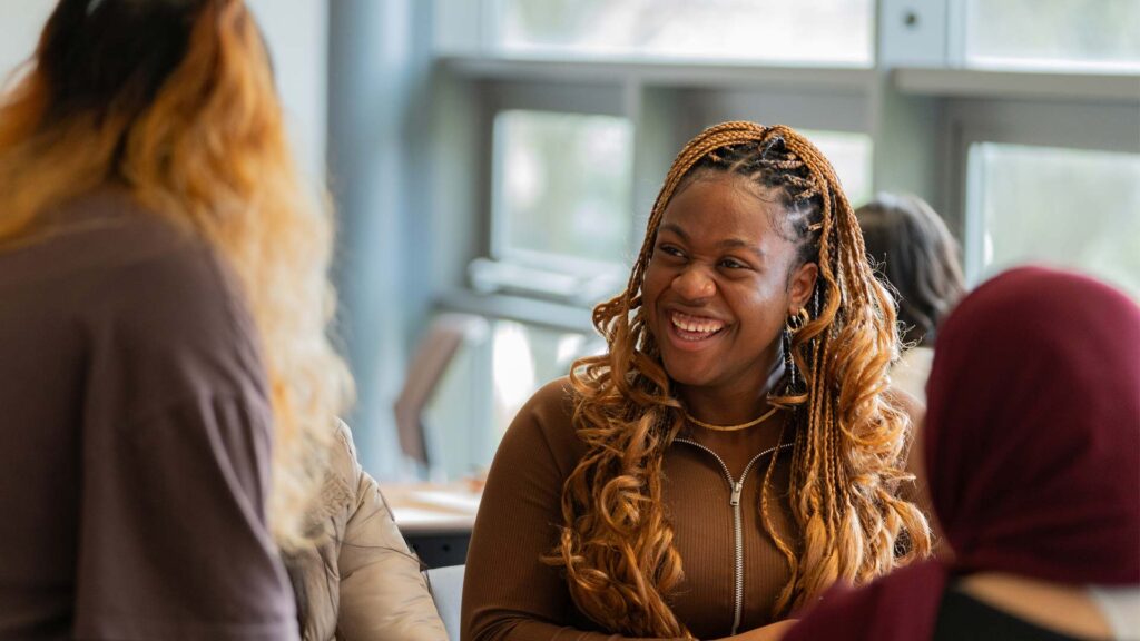 A student smiles while talking to other students