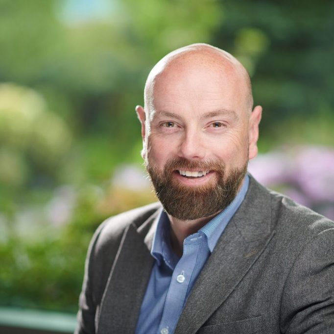 Adrian smiles at the camera against a green background.