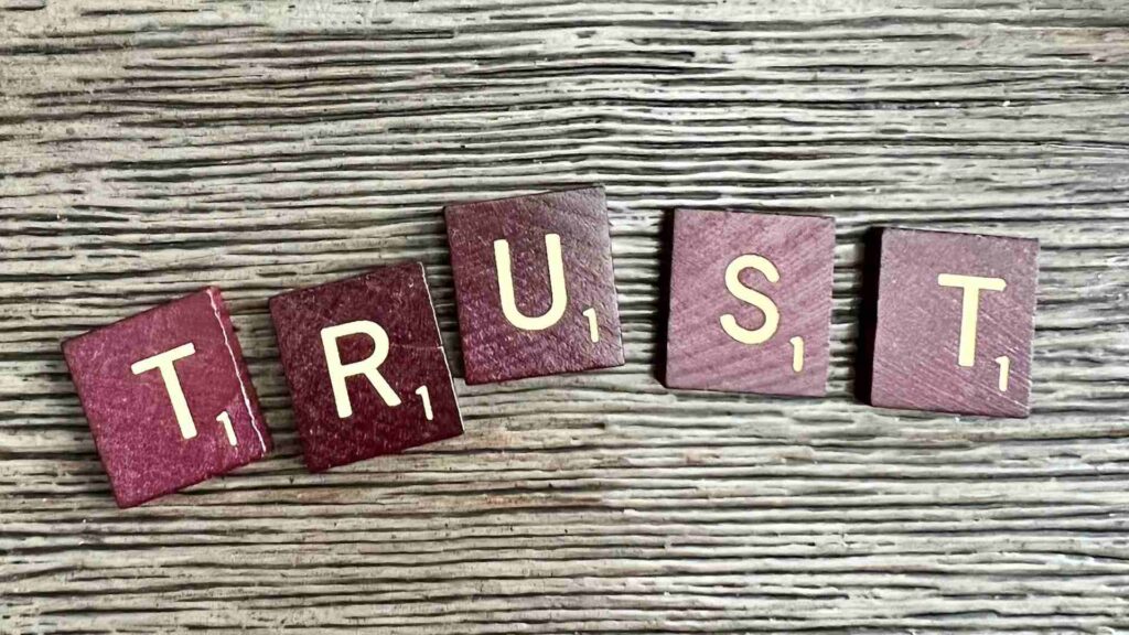 Wooden Scrabble-like tiles that spell the word 'trust'.